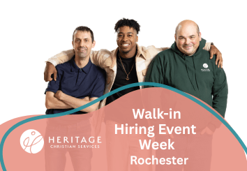 Three smiling men with arms around each other stand above a sign that reads, Walk-in Hiring Event Week Rochester, Heritage Christian Services, inviting everyone to join the upcoming walk-in hiring event.